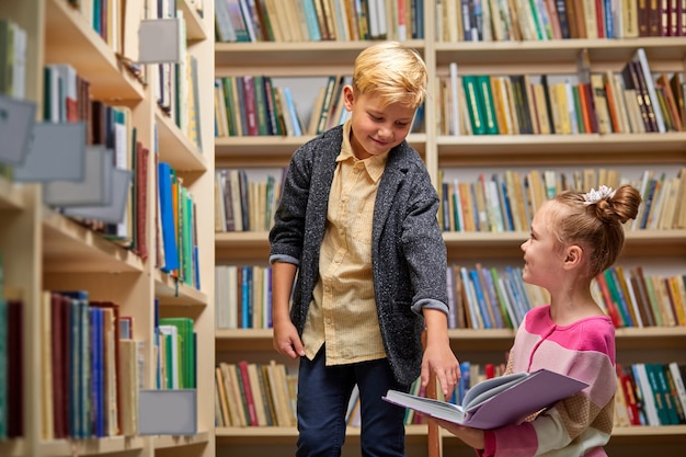 学校の図書館で授業の準備をしている学校の子供たち、一緒に教科書を読んで話し合っている、教育の概念