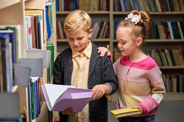 学校の図書館で授業の準備をしている学校の子供たち、一緒に教科書を読んで話し合っている、教育の概念