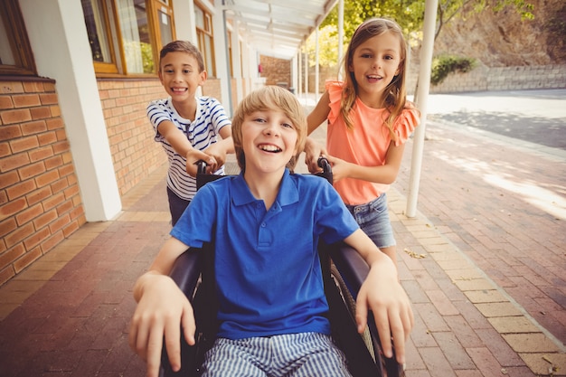 School kids pushing a boy on wheelchair