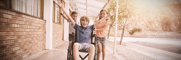 School kids pushing a boy on wheelchair