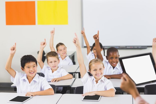 School kids raising hand in classroom