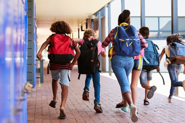 School kids running in elementary school hallway back view
