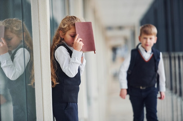 Photo school kids in uniform with books together in corridor conception of education