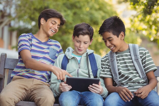 School kids using digital tablet on bench