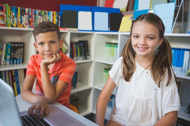 School kids using a laptop in library