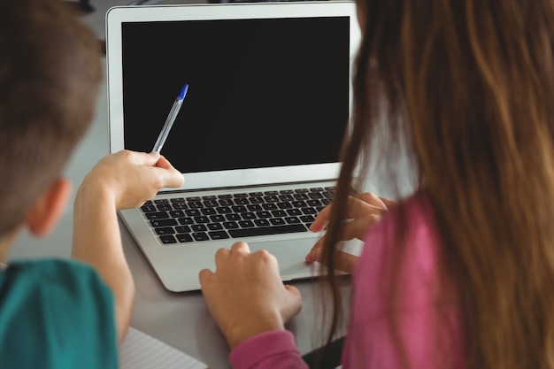 Bambini della scuola che utilizzano computer portatile nella biblioteca