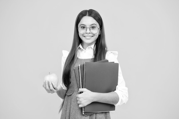 School kind tiener student meisje met rugzak houd appel en boek geïsoleerd op geel