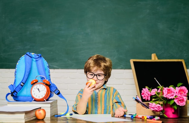 School lunch schooljongen tijdens de lunch grappige kleine jongen in glazen zit aan bureau in klas kind