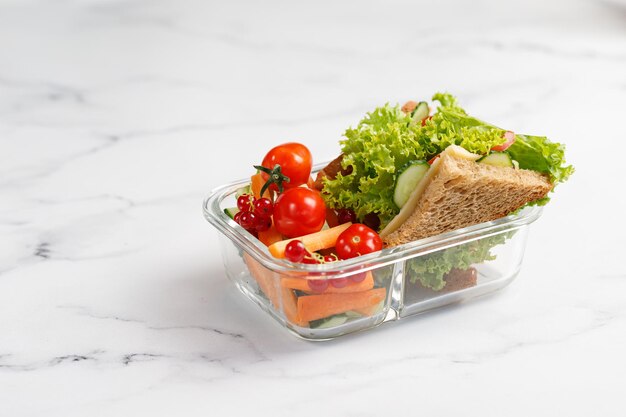 School lunch with a sandwich toasts vegetables snack with kid's hands Container glass box 