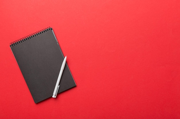 Photo school notebook on a colored background spiral black notepad on a table top view