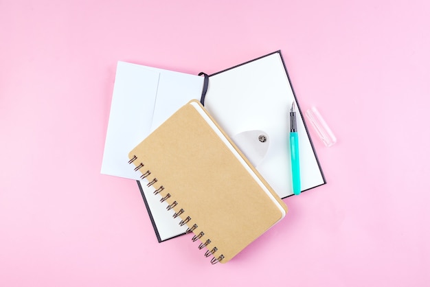 School notebook on a pink background, spiral notepad on a table