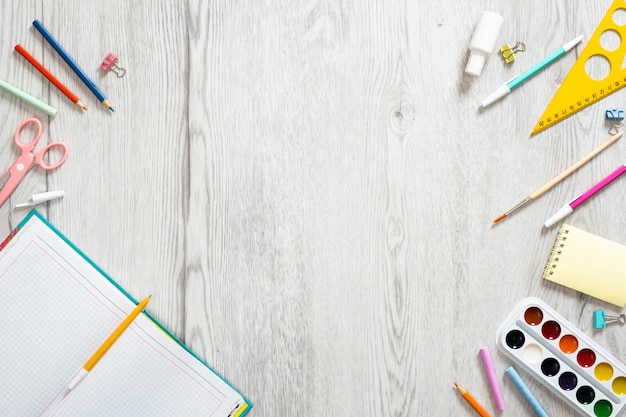 School notebook and various supplies on wooden background. Back to school concept.