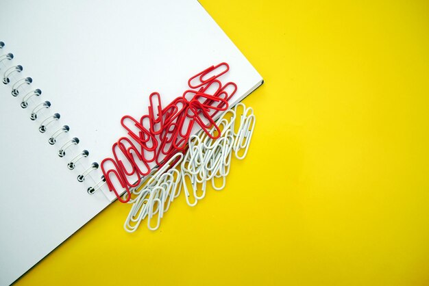 School notebook with red and white paper clips on yellow background spiral notebook on table Copy sp
