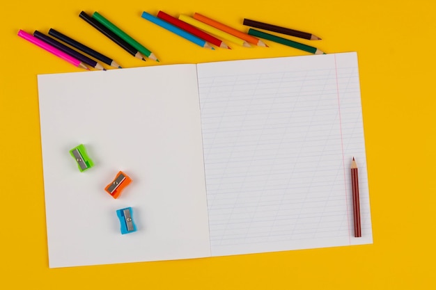 Photo school notebook on a yellow background with copy space text colorful pencils pencil sharpeners