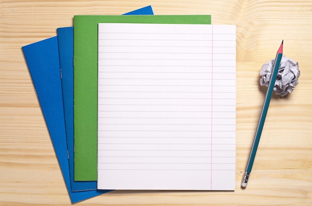 School notebooks empty sheet crumpled paper and pencil on wooden desk top view Space for text