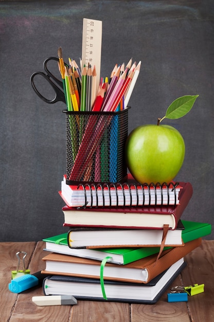 School and office supplies on classroom table in front of blackboard