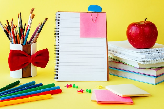 School and office supplies on classroom table on yellow