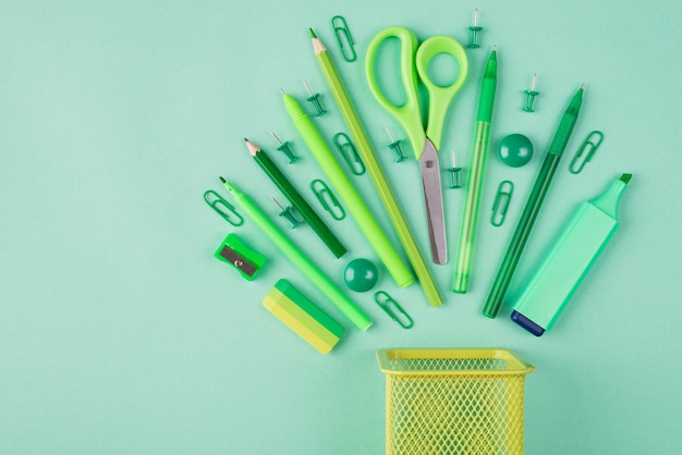 School and office supplies concept. Top above overhead view flatlay photo of green arranged stationery isolated on turquoise background