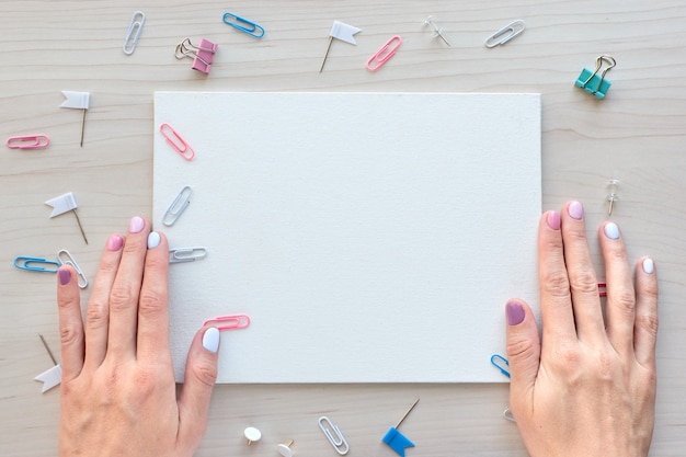 School office supplies on wooden background. Back to school concept. White board with hands for copy space. Top view ready for your design.