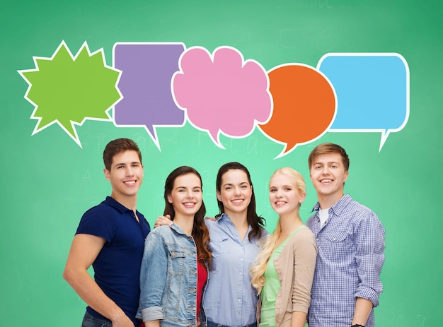 school, onderwijs, communicatie en mensen concept - groep lachende tieners over groene bord achtergrond met tekst bubbels