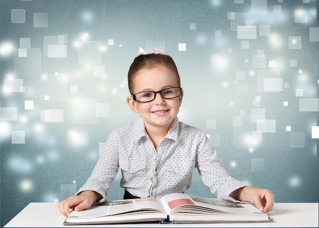 Foto bella ragazza della scuola con gli occhiali rossi che legge un libro