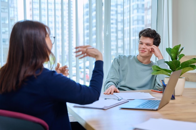 School psychologist supporting guy student sitting in office of educational building