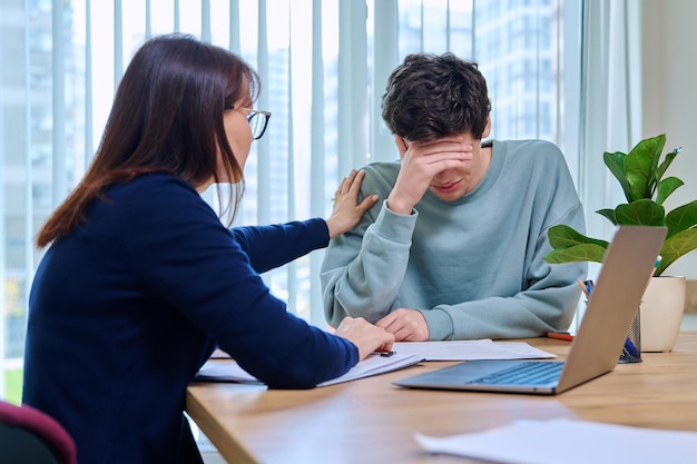 school psychologist supporting guy student sitting in office of educational building