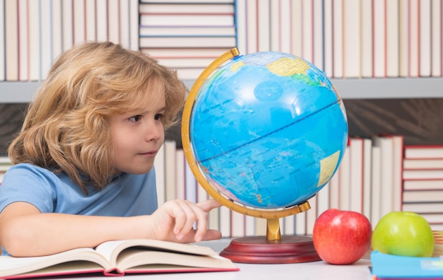 Foto allievo della scuola che guarda il globo nella lezione di geografia della biblioteca scuola e bambini carino bambino biondo con ab