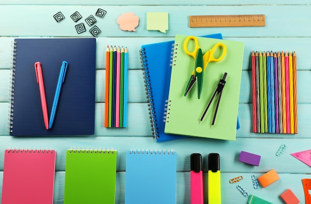 School set with notebooks scissors and colored pencils on wooden blue background