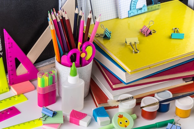 School stationery on a table in front of blackboard.