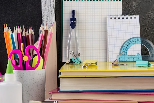 School stationery on a table in front of blackboard,