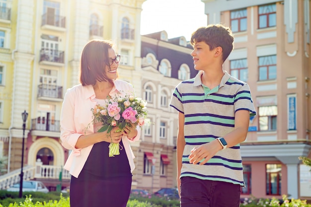 School student congratulates his teacher with bouquet