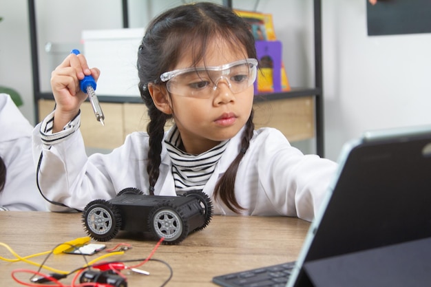 ロボットカーを作る学校の生徒 ロボット学校の女の子がロボットを作る コンストラクターから管理された子供がロボットの組み立てを学ぶ