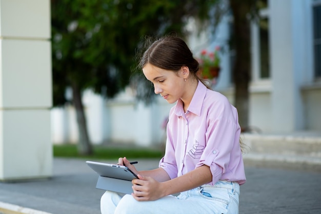 Una studentessa sui gradini della scuola con un gadget in mano education generation z