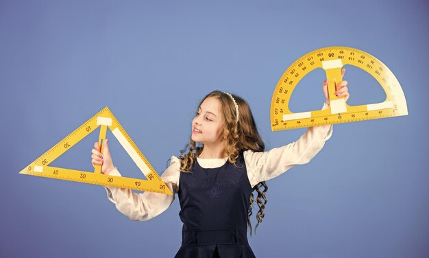 Geometria di studio degli studenti della scuola uniforme scolastica per bambini tenere il righello concetto di istruzione scolastica dimensionamento e misurazione imparare la matematica teoremi e assiomi concetto intelligente e intelligente ragazza con un grande righello