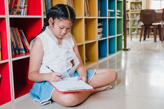 사진 학교 학생 십 대 소녀는 도서관에서 숙제를 하 고 그리기입니다. 교육 및 문맹 퇴치 개념입니다.