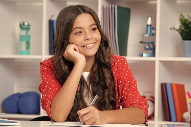 School student writing in exercise book studying in classroom Happy schoolgirl