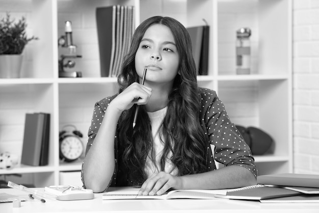 School student writing in exercise book studying in classroom serious teenager schoolgirl