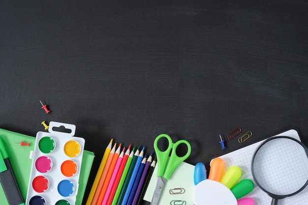 School supplies on black board background.