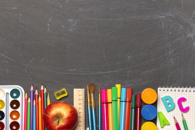 School supplies on black chalkboard background.