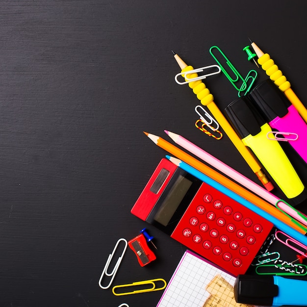 School supplies on black table. Flat layout.