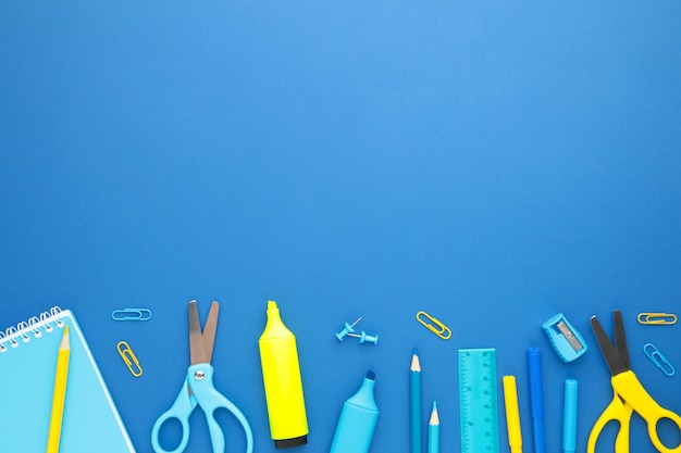 School supplies on blue wall with copy space. Back to school. Flat lay.