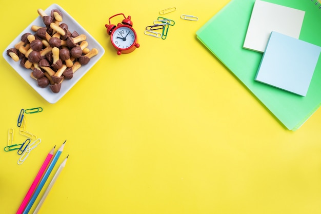 School supplies and cookies for a snack on the yellow table with copy space. concept school