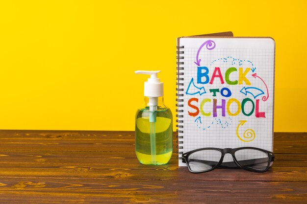 School supplies and hand sanitizer on desk. Pandemic education concept