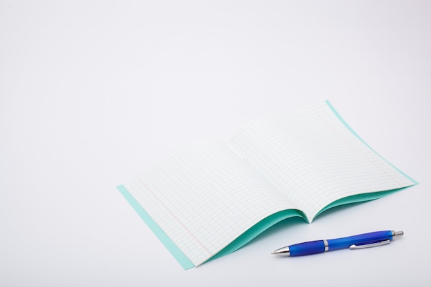 School supplies isolated on white background. photo on the topic of studying at school. notebook and a blue ballpoint pen on a white background