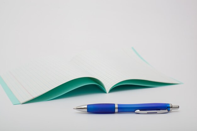 School supplies isolated on white background. photo on the topic of studying at school. notebook and a blue ballpoint pen on a white background