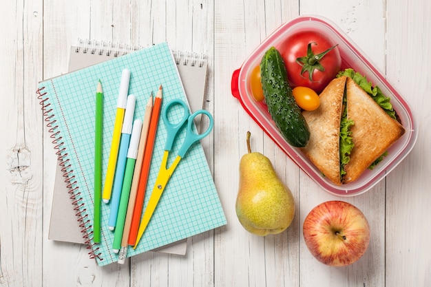 Школьные принадлежности, ланч-бокс с бутербродом, овощами и фруктами