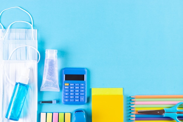 Photo school supplies, medical masks and hand sanitizer. back to school after covid-19 pandemic.