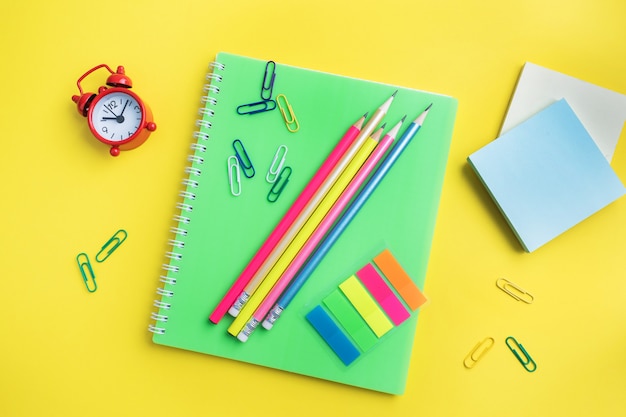 School supplies, notebooks pencils on yellow background with copy space.