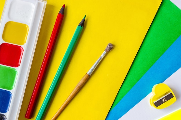 Materiale scolastico: colori, carta colorata, matite, pennello e temperino. il concetto di creatività e disegno dei bambini.